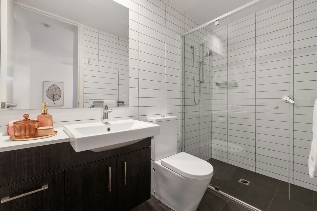 Walk-in dusch med guldfärgade detaljer och naturlig stenmosaik
